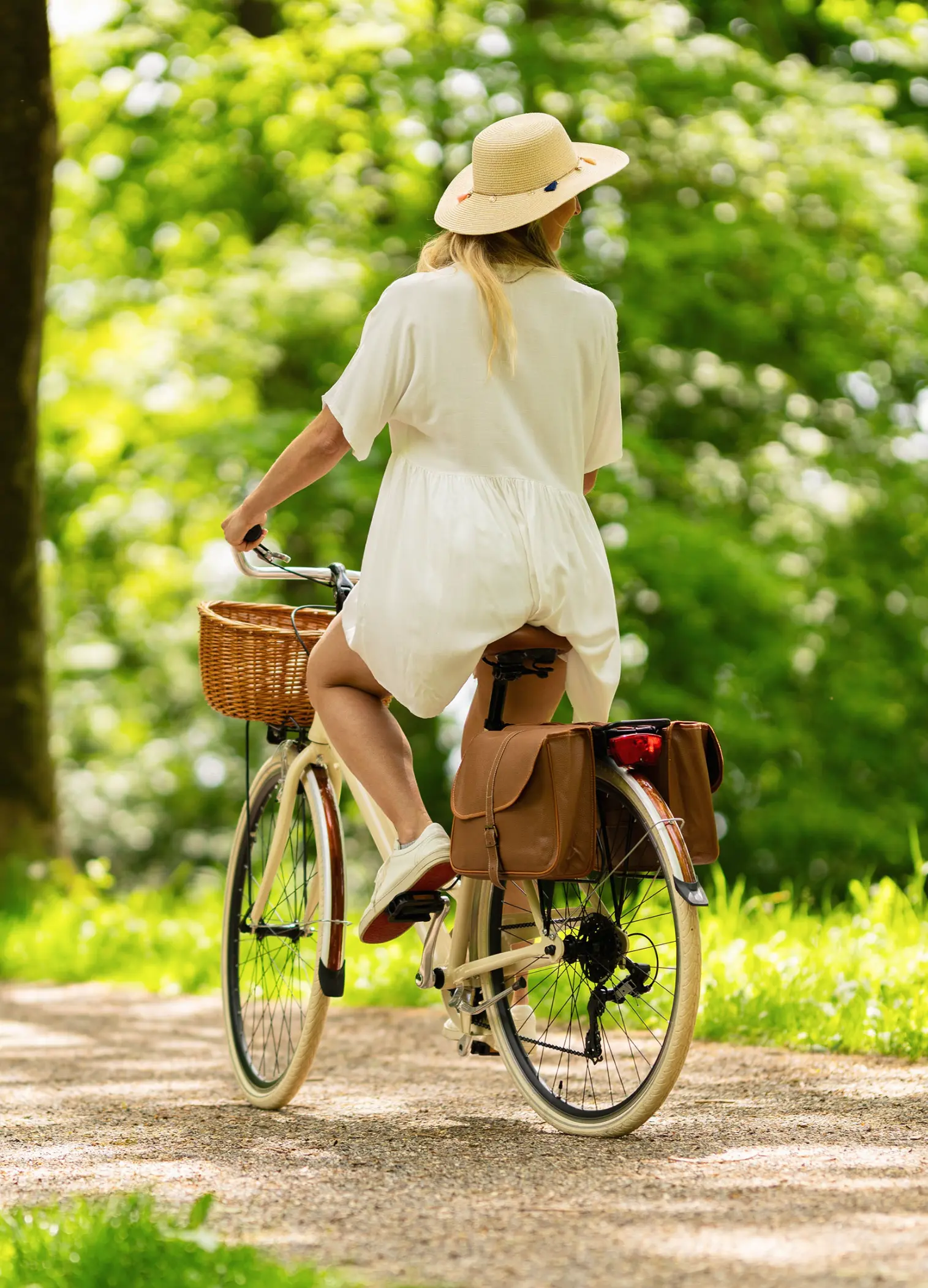 Frau fährt mit dem Fahrrad durch eine grüne Allee