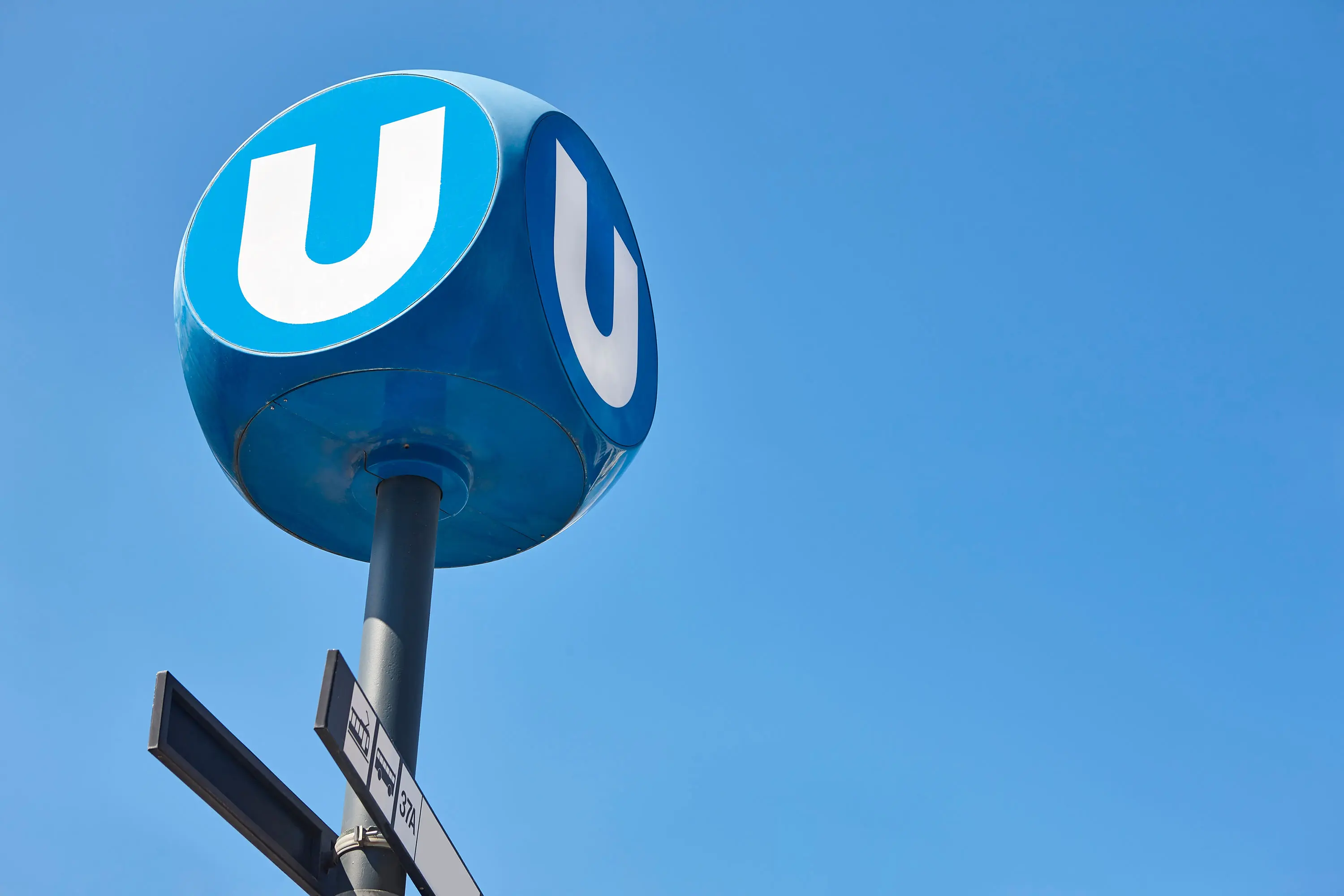 Schild einer Wiener U-Bahn-Station vor blauem Himmel